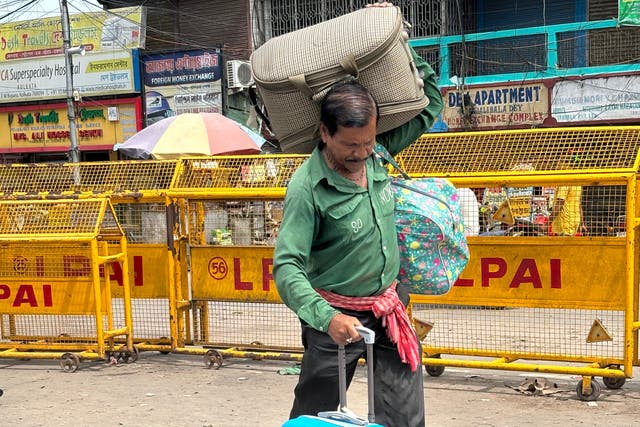 <p>A porter carries the luggage of a Bangladeshi national upon his arrival in India</p>